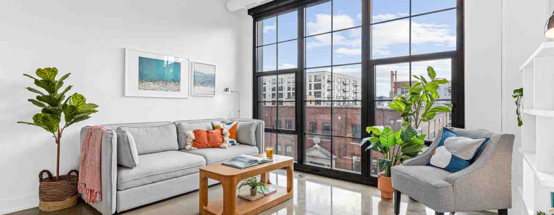 Panoramic loft interior with exposed brick, high ceilings, and large windows - warehouse apartments for rent