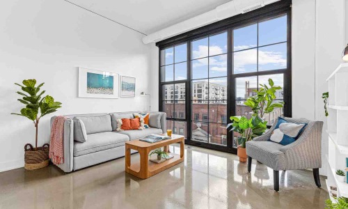 Panoramic loft interior with exposed brick, high ceilings, and large windows - warehouse apartments for rent