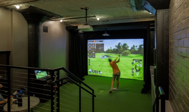 a person playing golf in a simulator area